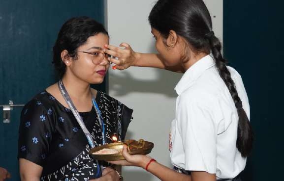 Student applying Tilak to educator