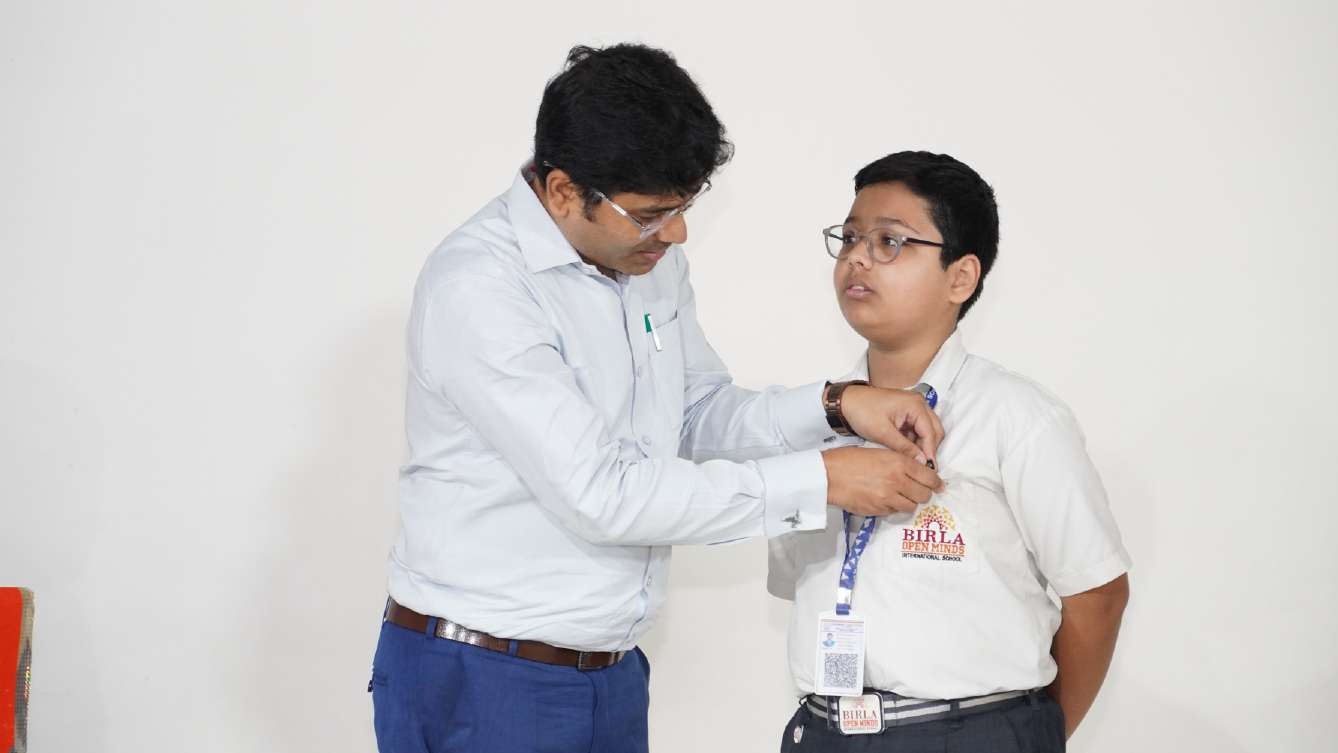 Teacher Pinning Leadership Badge onto Prefect Uniform