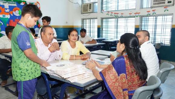 Student in sports jersey consulting with teacher alongside parents