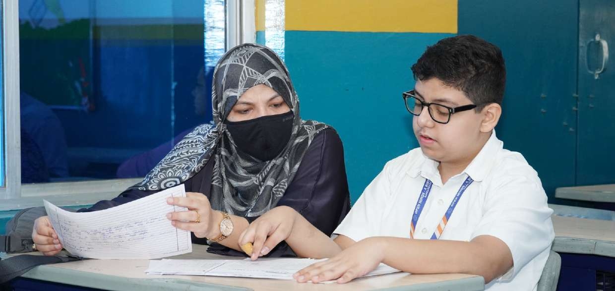 Mother and student in glasses reviewing exam paper line-by-line