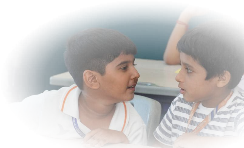 Two primary boys in animated classroom conversation