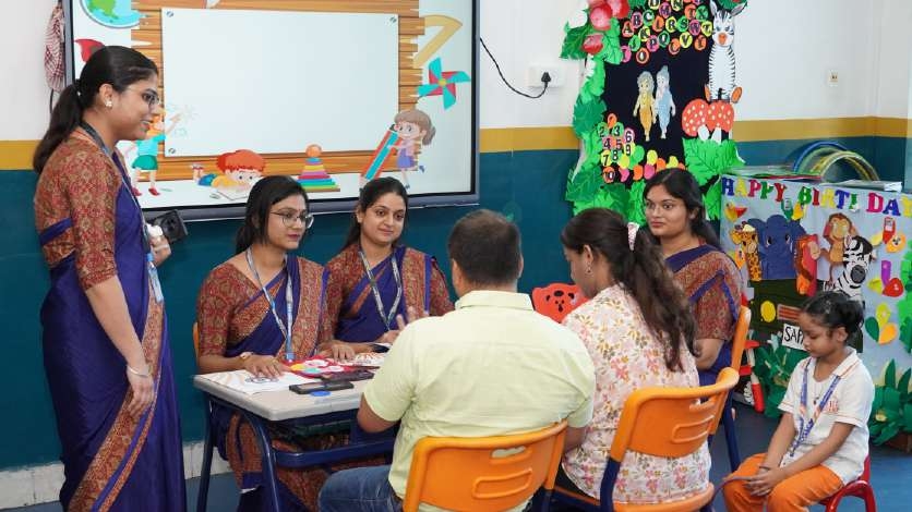 Primary educators in sarees consulting with parents at round table