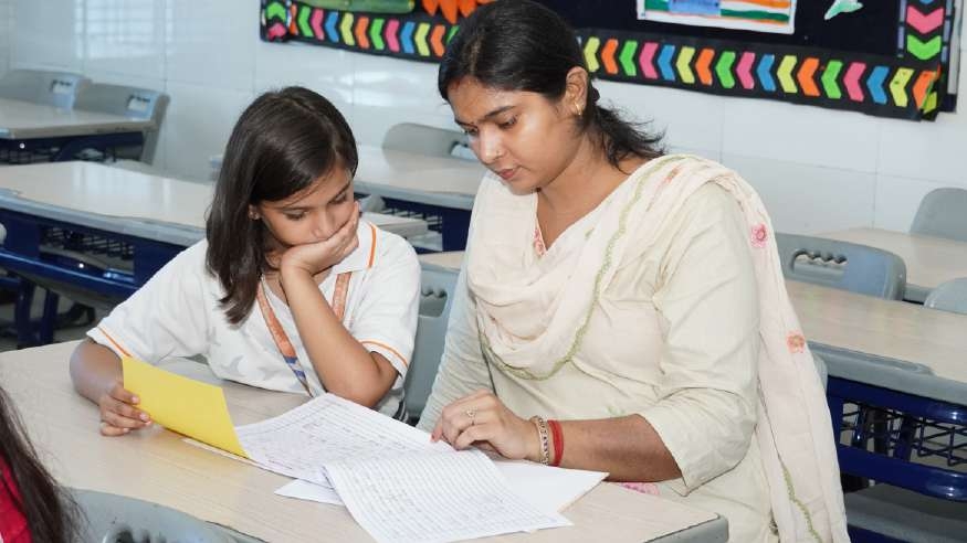 Mother in cream salwar guiding daughter through exam papers