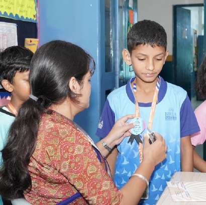 Teacher pinning special merit badge onto student's school uniform