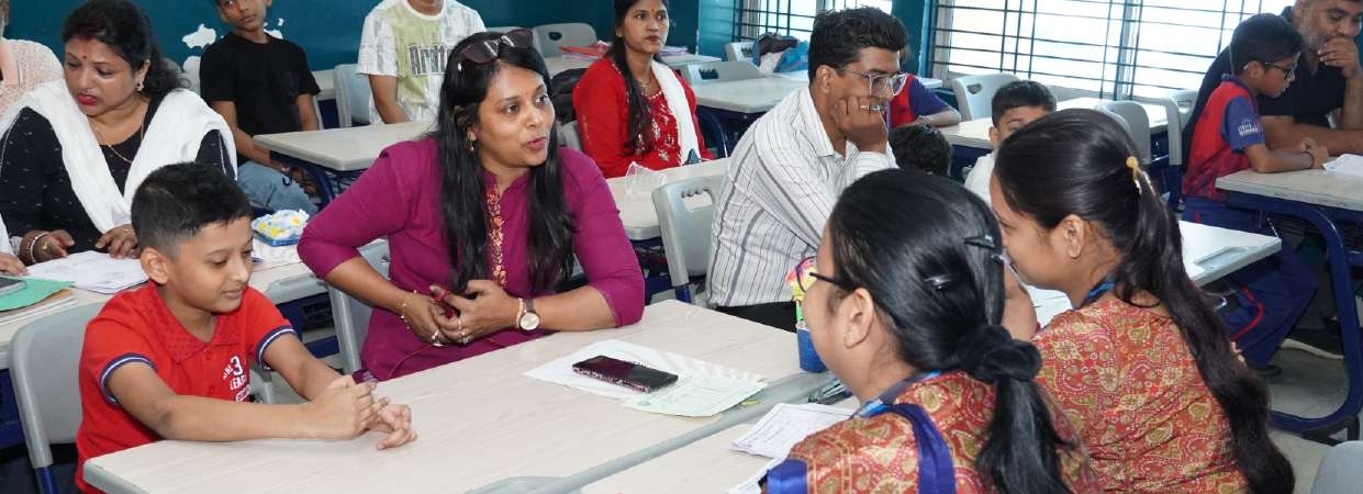 Mother in magenta kurti and student in red polo discussing goals with educators