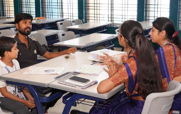Father and son in black shirt consulting with two teachers