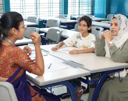 Teacher discussing progress with student and mother in headscarf