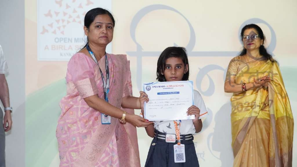 Teacher in pink saree awarding certificate to smiling girl student