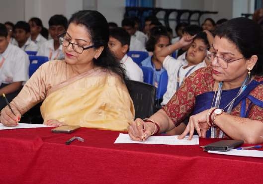 Faculty judges taking notes and evaluating performances at red tablecloth desk