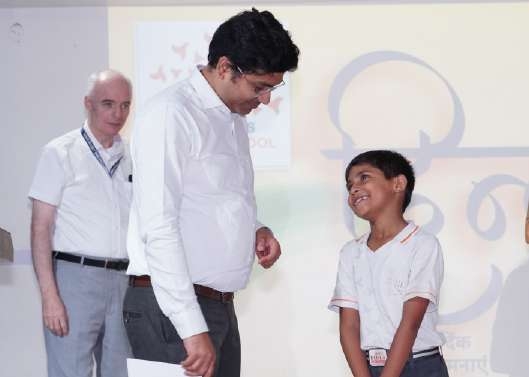 Principal and guest mentor smiling encouragingly at happy young boy on stage