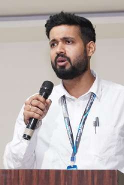 Faculty mentor with beard delivering speech from lectern