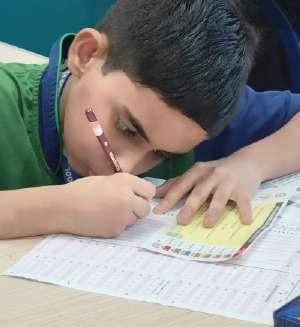 Primary student carefully solving questions on OMR sheet